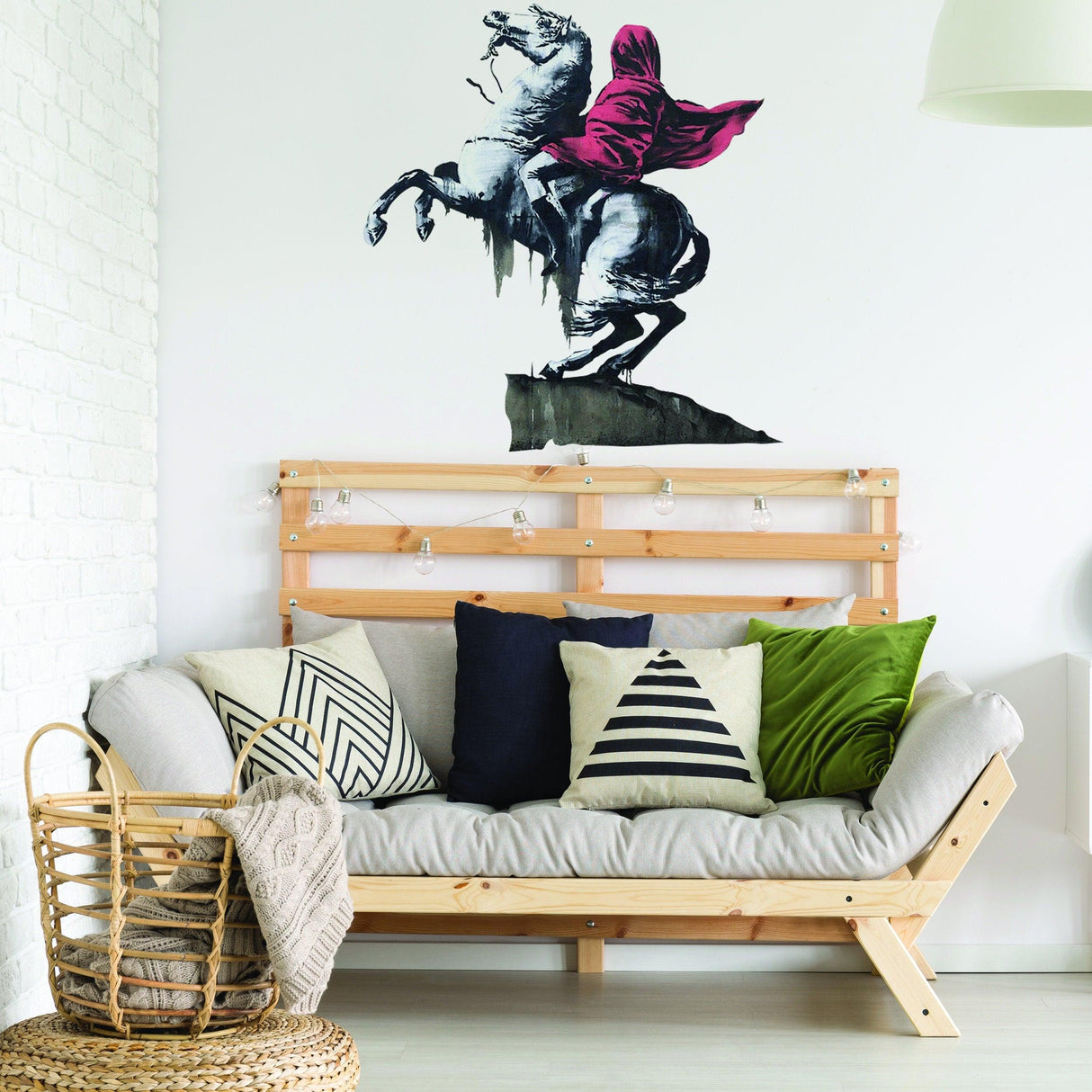 Banksy Napoleon vinyl wall sticker on white wall above modern sofa with decorative pillows