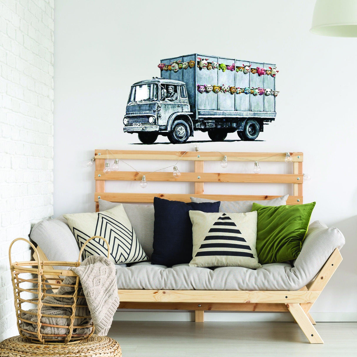 Banksy Animal Truck Vinyl Wall Sticker on white wall above a modern sofa with colorful cushions.