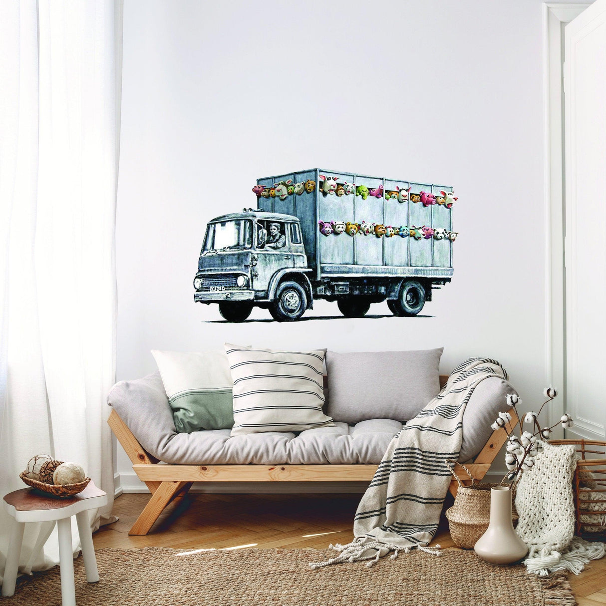 Banksy Animal Truck Vinyl Wall Sticker on a white wall above a cozy sofa, adding urban decor to a stylish living room.