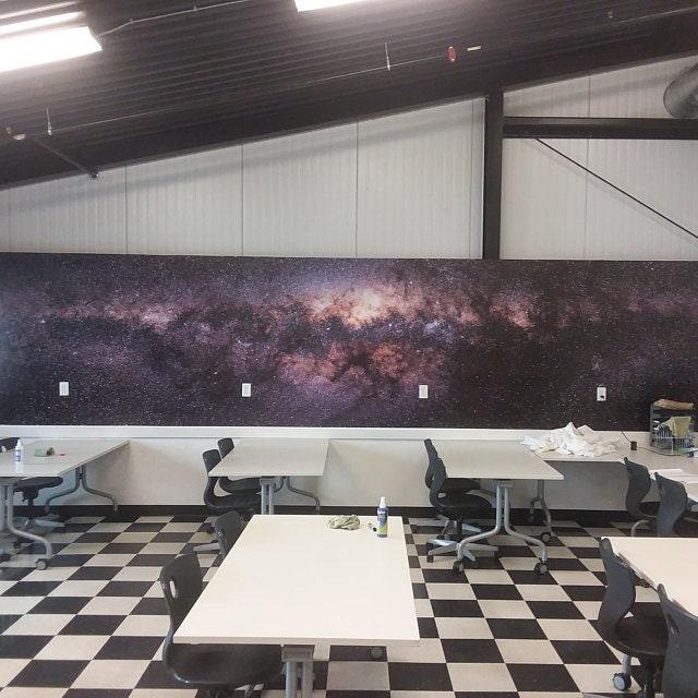 Classroom with a cosmic wall mural featuring a galaxy design, enhancing the learning environment.