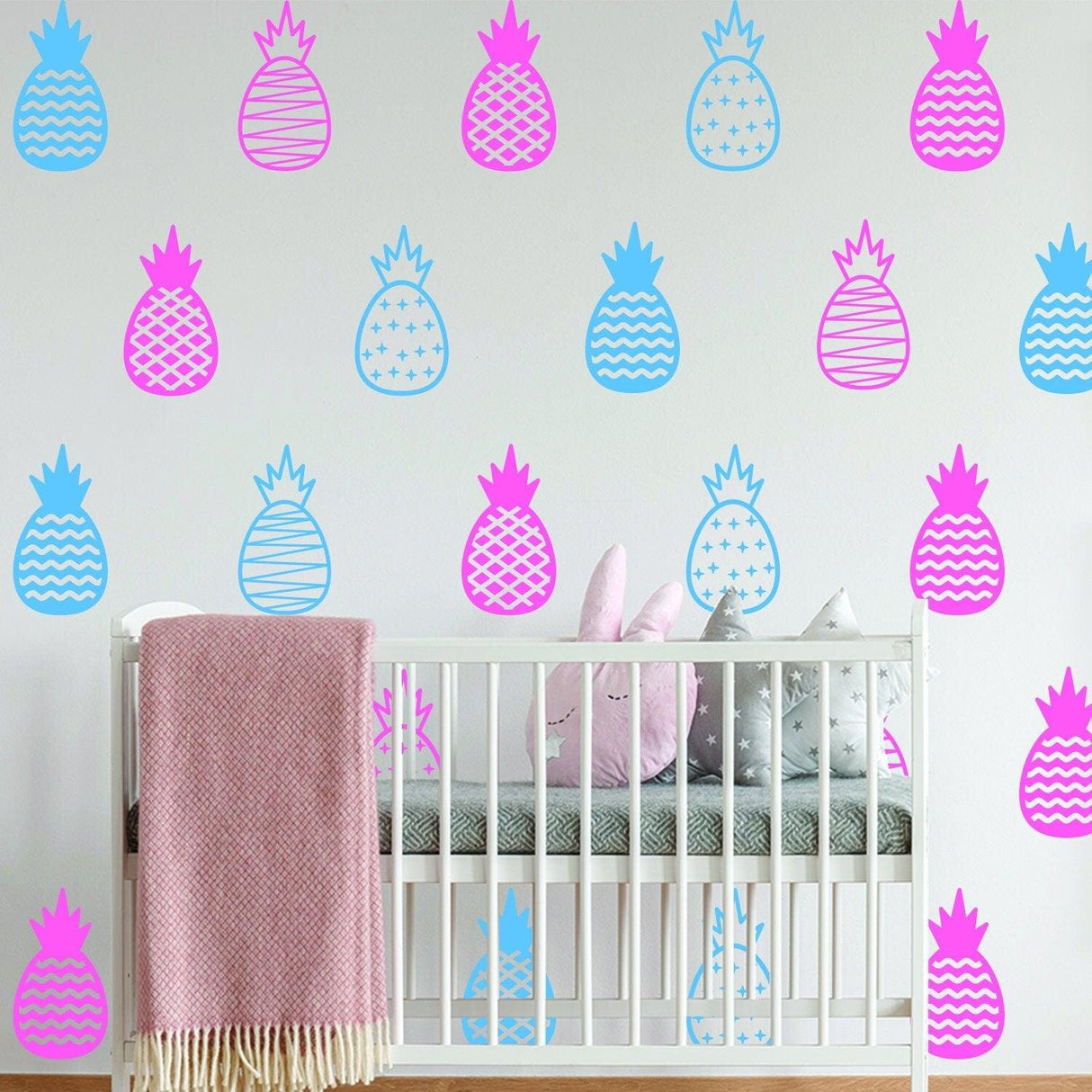 Colorful pineapple wall decals in pink and blue decorating a nursery, adding a playful touch to the decor.
