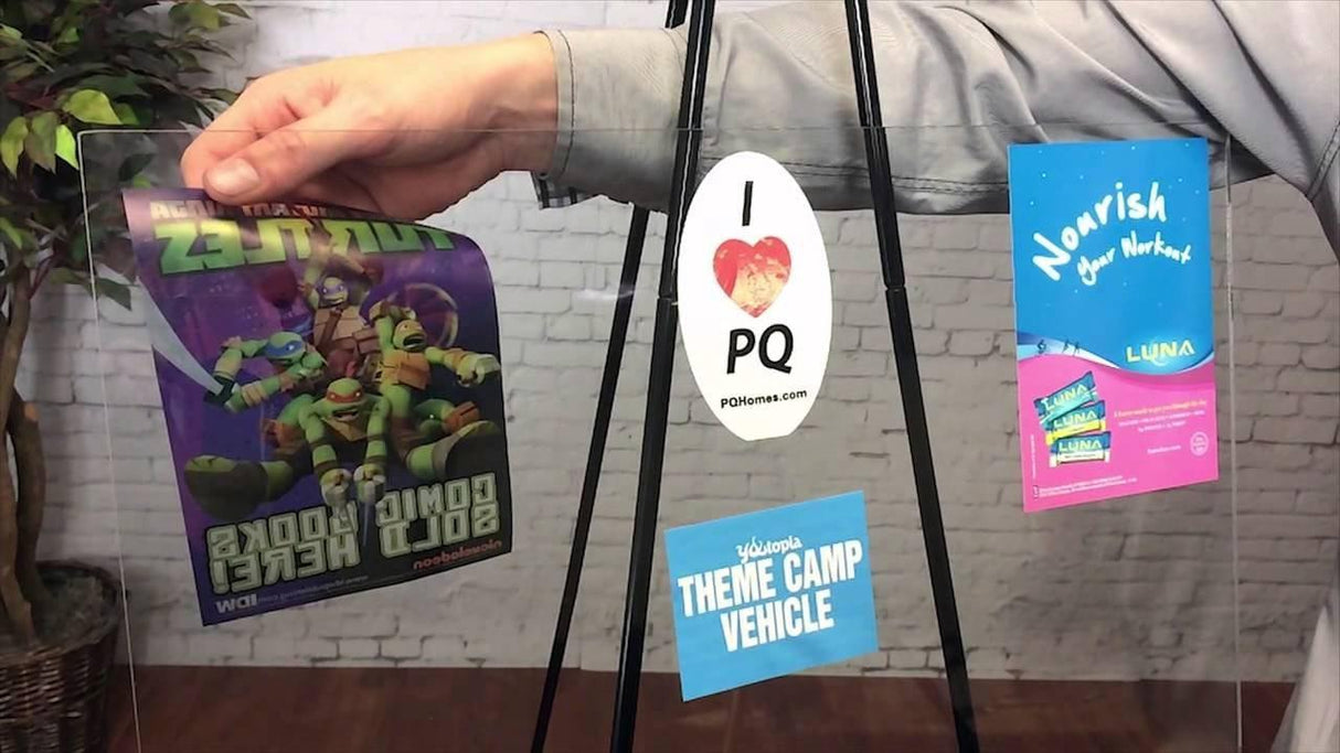 Person holding custom static cling vinyl stickers on a clear display, showcasing vibrant designs and messages.