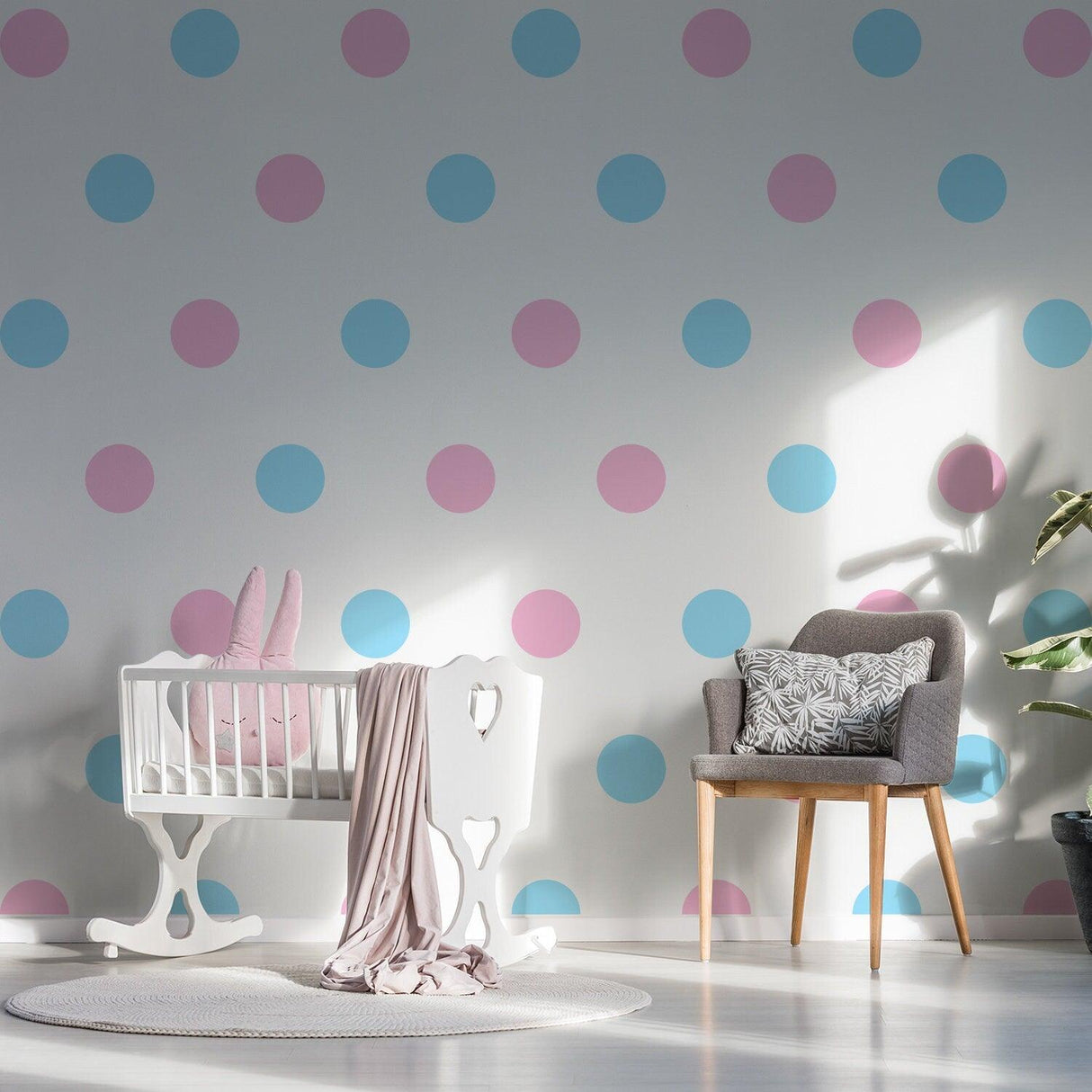 Nursery room with pink and blue circle wall decals, featuring a crib and a comfy chair, creating a charming decor.
