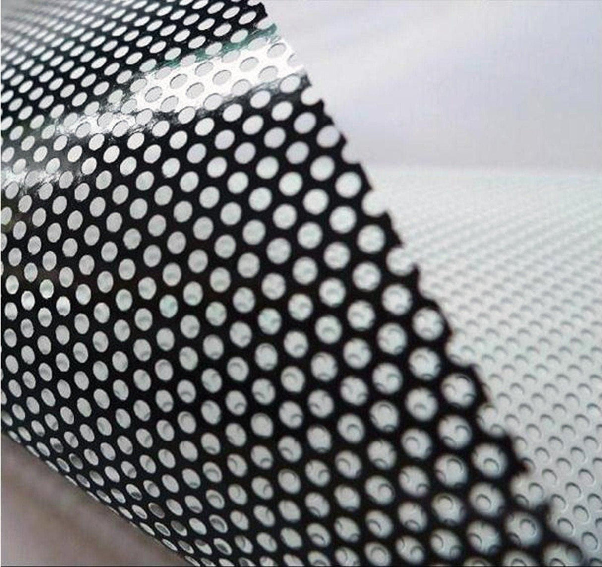 Close-up of black and white perforated vinyl material for car decals and stickers.