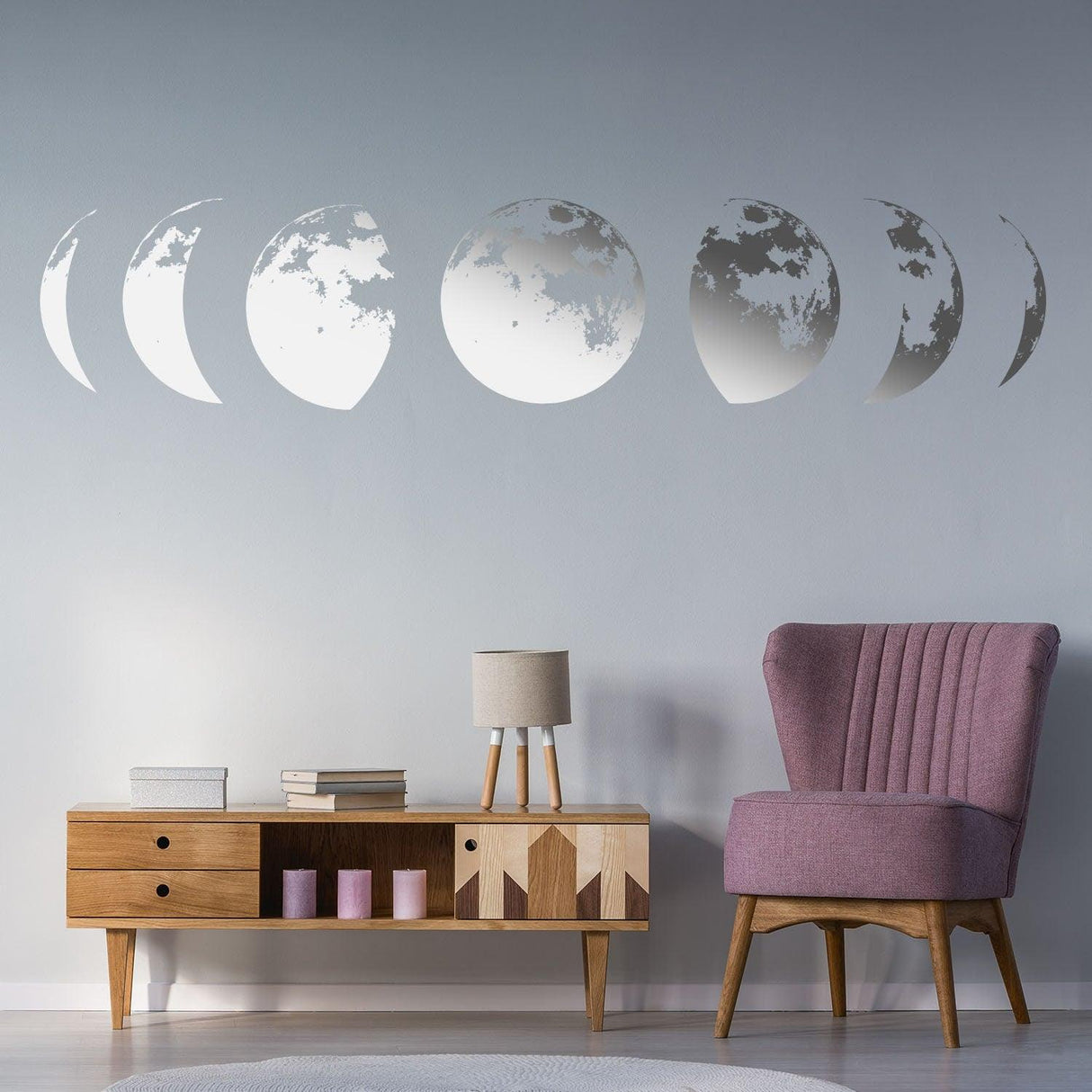 Moon phases wall decor decal in gold above a modern wooden sideboard and a pink armchair for elegant home styling.
