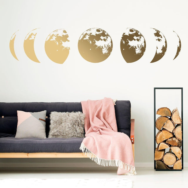 Gold moon phases wall decor decal adorning a stylish living room with cozy couch and decorative blanket.