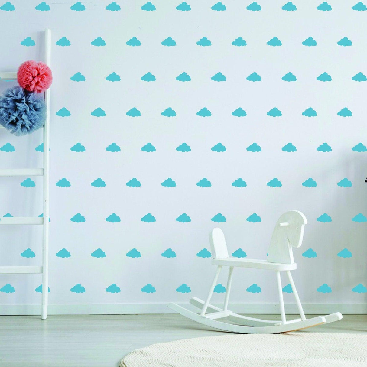Light blue cloud wall decals decor in a nursery with a white rocking horse and playful pom-pom accents.