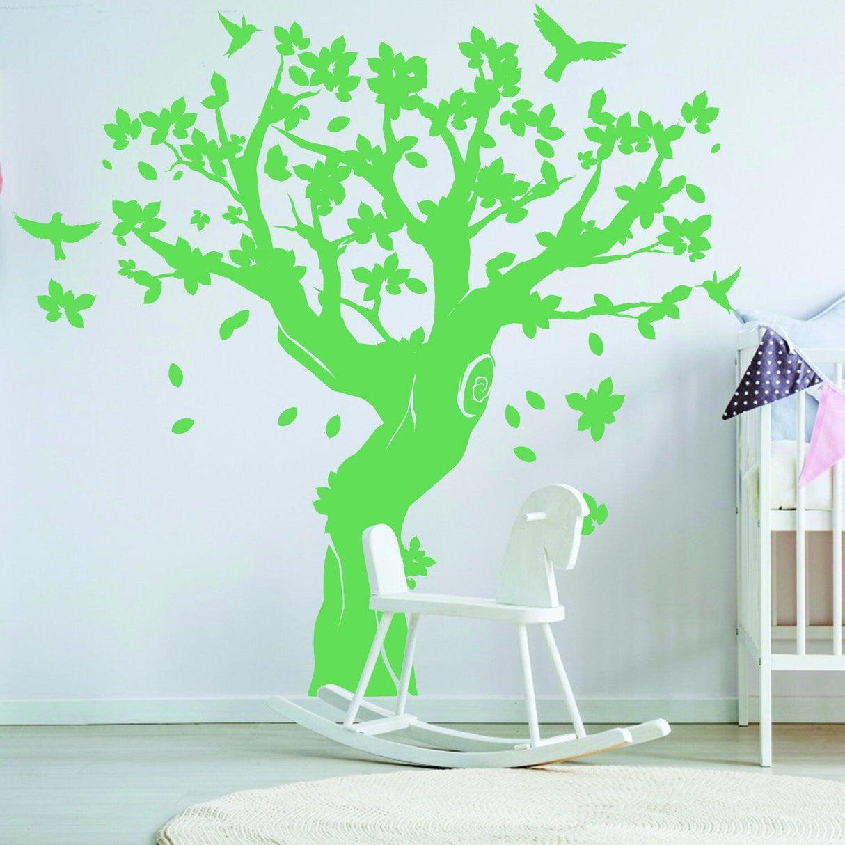 Green tree wall decal with flowers and birds in nursery, adding charm and whimsy to kids' room decor.