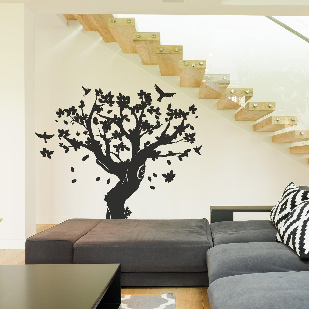 Black tree wall decal with birds and flowers in a modern living space, perfect for kids' rooms or nurseries.