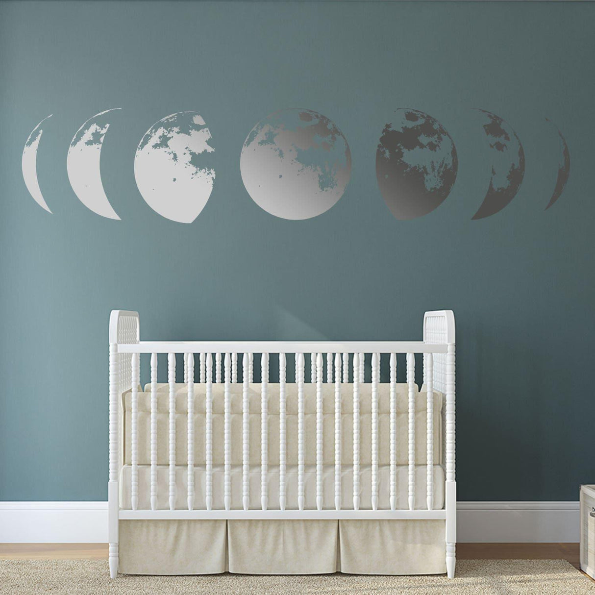 Moon phases wall decor decal in silver on a teal wall above a white crib, perfect for nursery decoration.