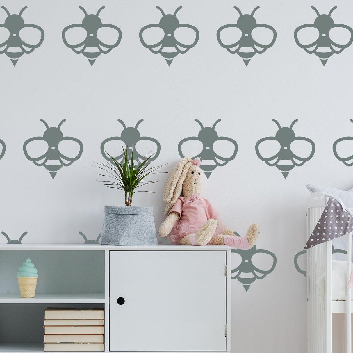 40x bee wall stickers in gray on nursery wall with a plush bunny and a plant decor.