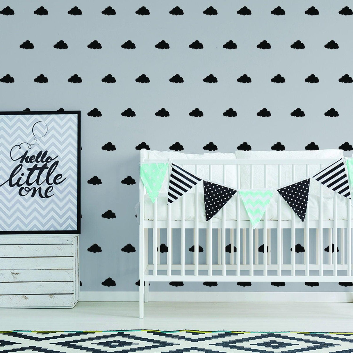 Modern nursery decor featuring black cloud wall decals, crib, and decorative bunting for a whimsical baby room.