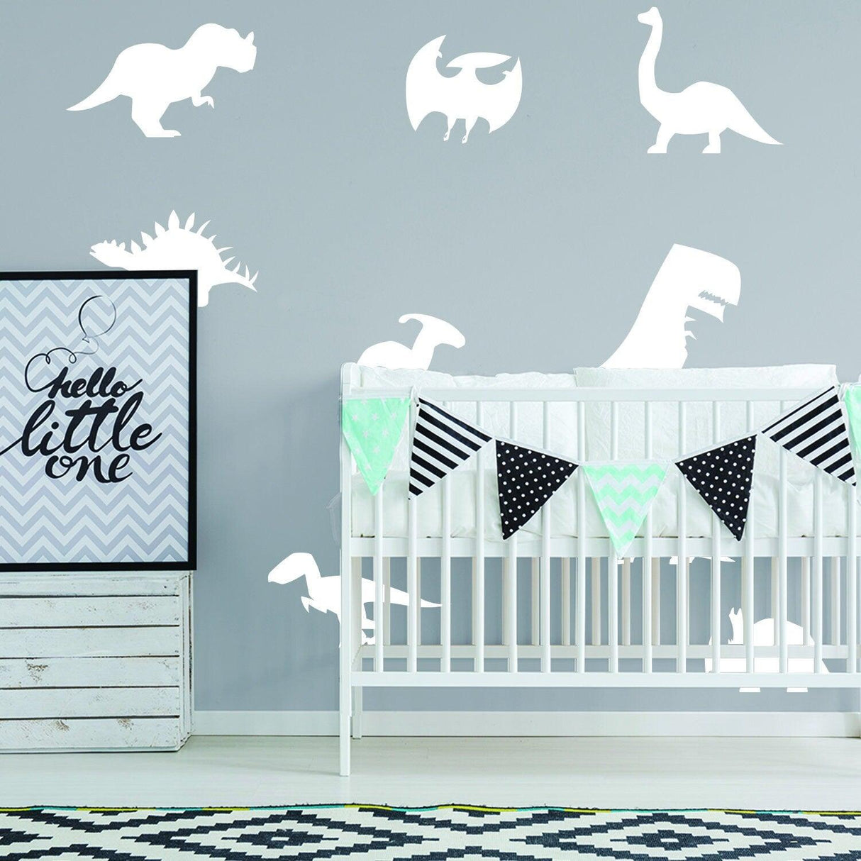 Glow in dark dinosaur wall decals above a crib with decorative bunting in a stylish nursery.