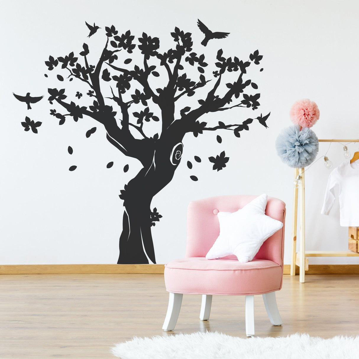 Tree wall decal decor in nursery with pink chair, creating a whimsical nature-inspired kids room.