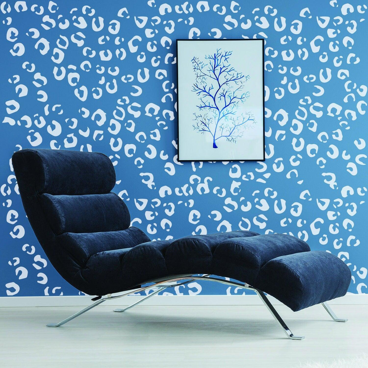 Modern lounge chair against a leopard print wall with a framed blue tree artwork.
