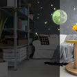 Glow in the dark full moon and stars wall sticker creating a celestial decor on bedroom ceiling.