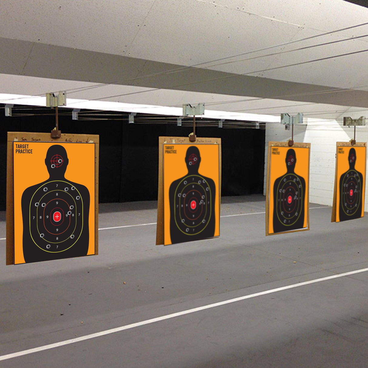 Four large silhouette shooting targets hanging in an indoor shooting range for practice.