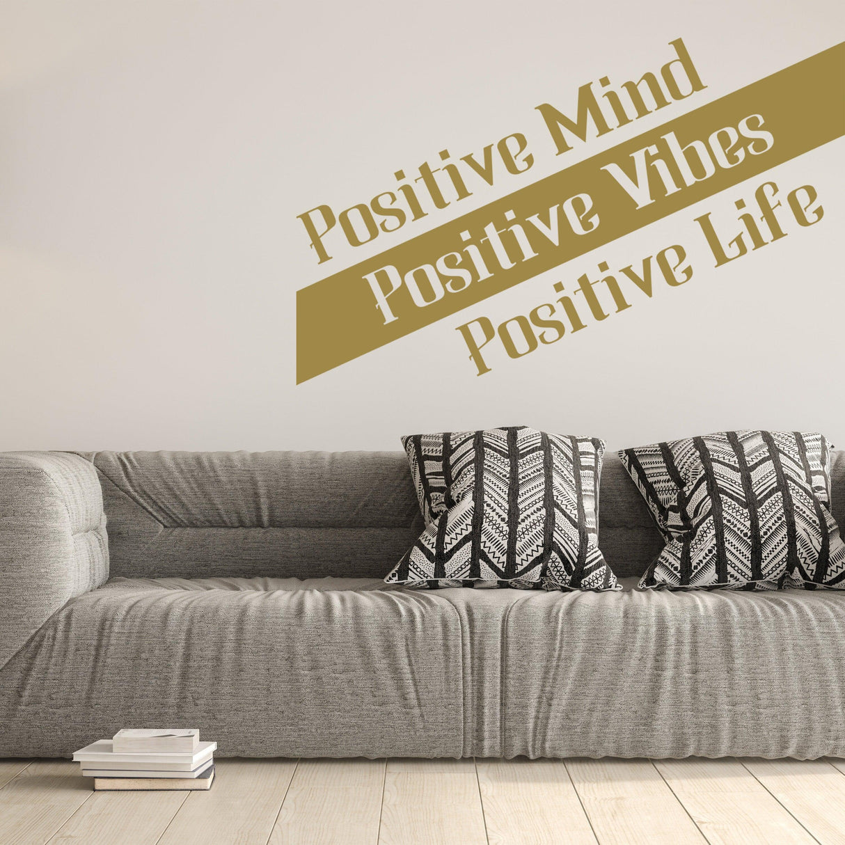 Inspirational wall decal saying 'Positive Mind, Positive Vibes, Positive Life' above a modern grey couch with patterned pillows.
