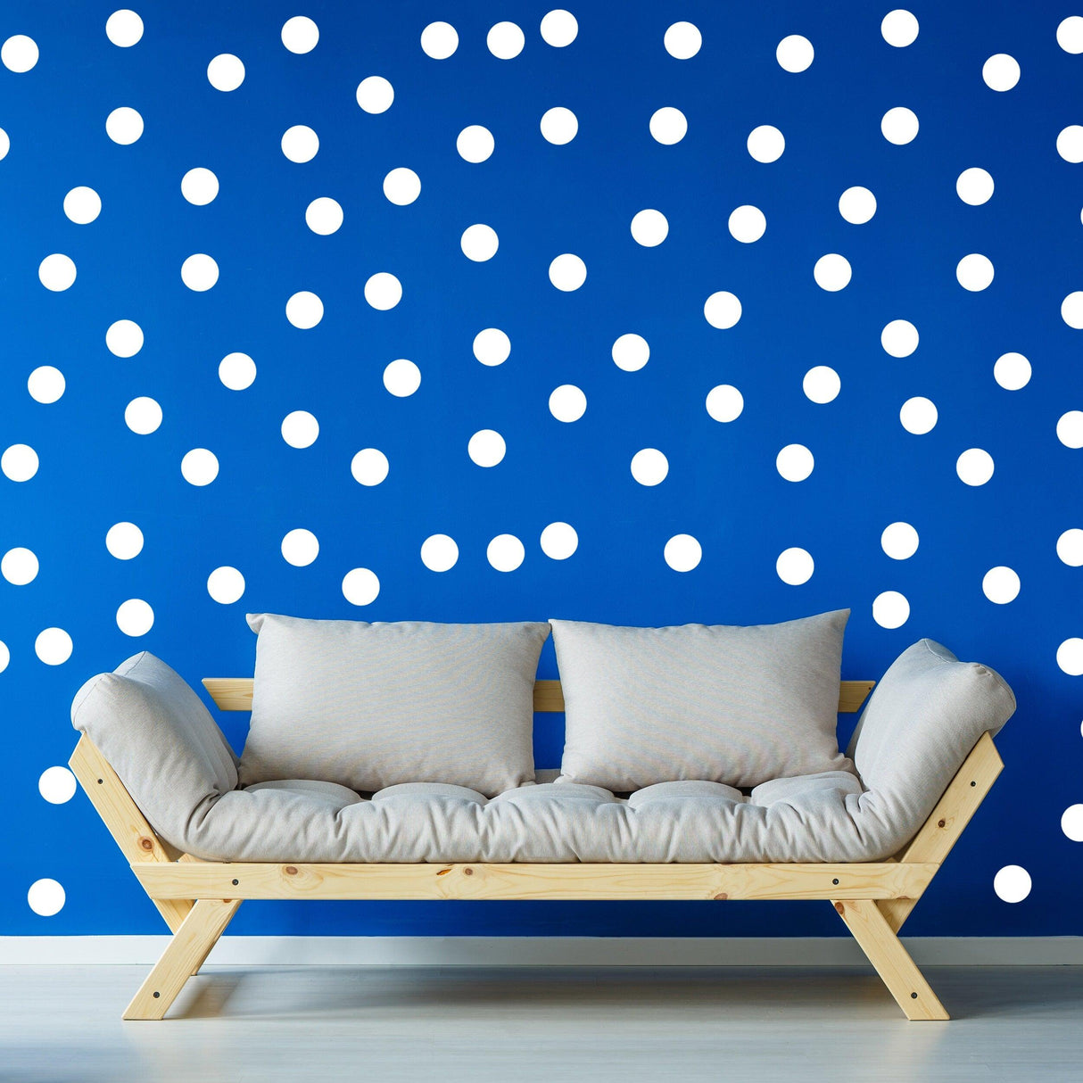 Stylish living room with a blue wall featuring white round circle dot stickers and a comfortable wooden sofa.