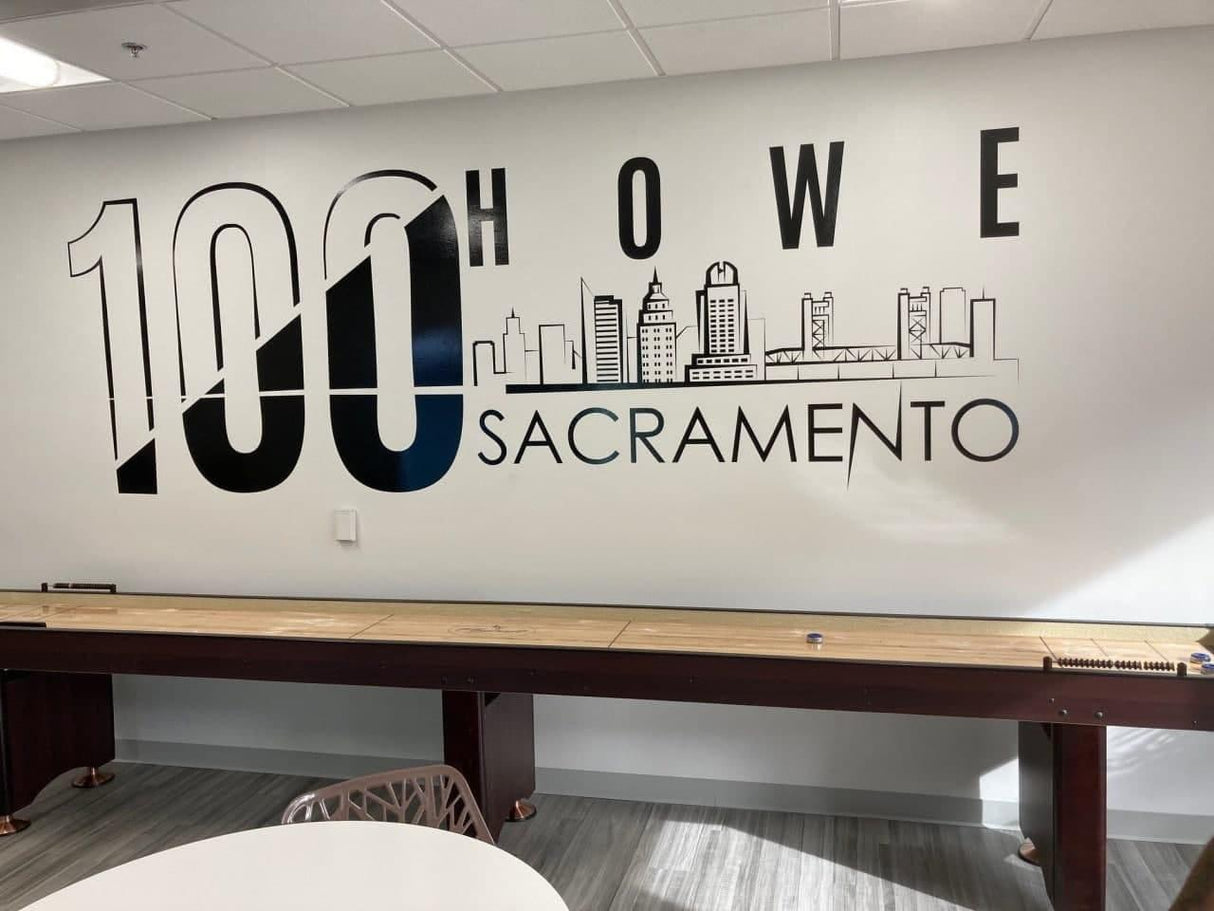 Custom wall decal featuring '100 Howe Sacramento' with skyline design in modern office setting.