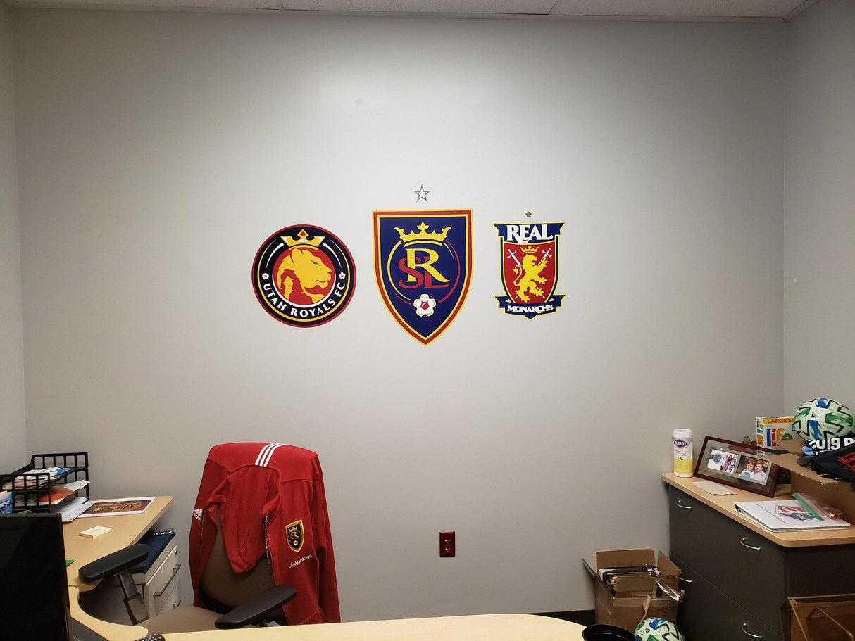 Wall display featuring three team logos and a red jacket in an office setting.
