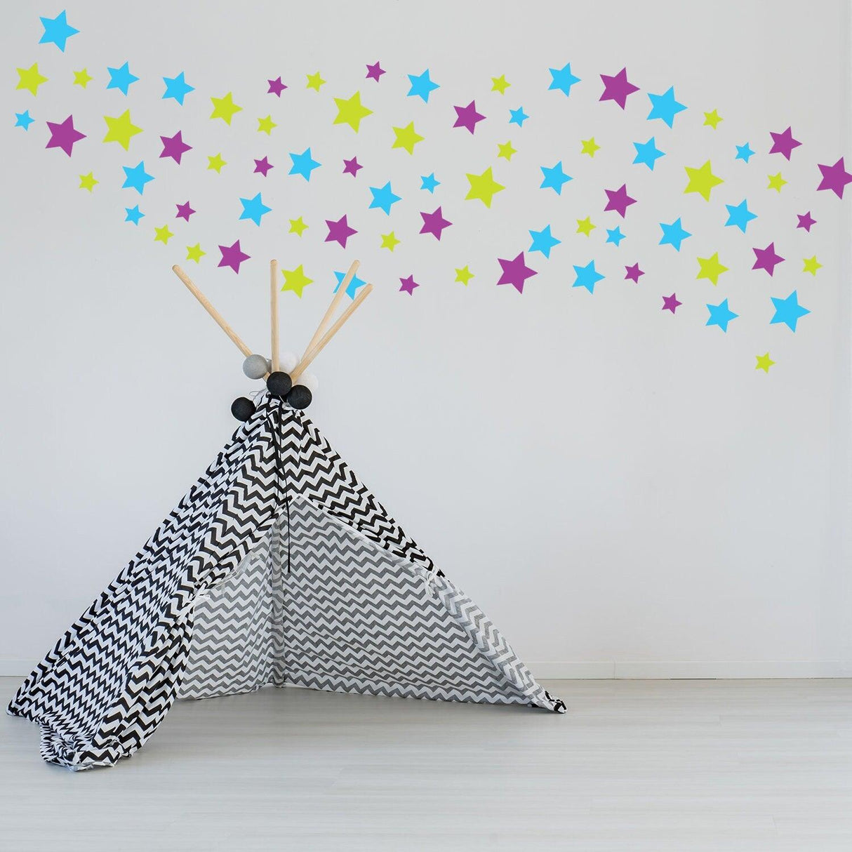 Colorful removable star wall decals above a black and white teepee in a child's nursery.