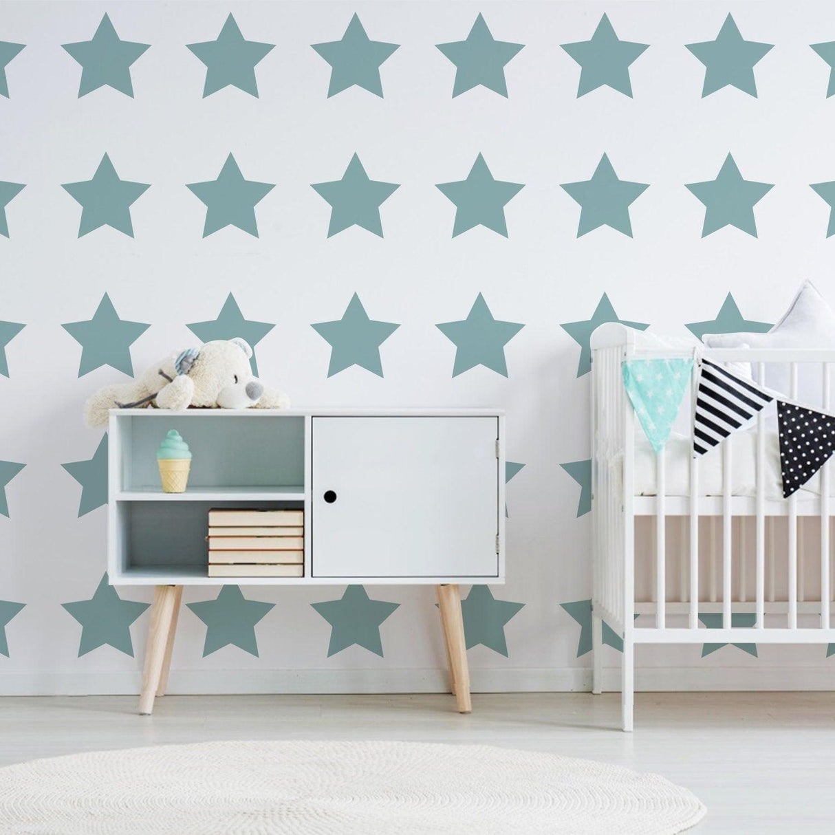 Nursery with 40x removable star wall decals in soft teal, featuring a crib and stylish storage unit.