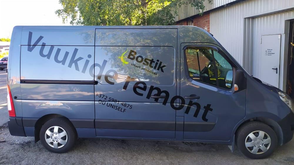 Gray commercial van with business branding and contact details on the side, parked outside.