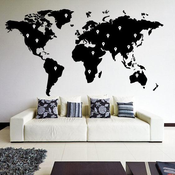 Large black world map wall decal with location markers above a modern white sofa.