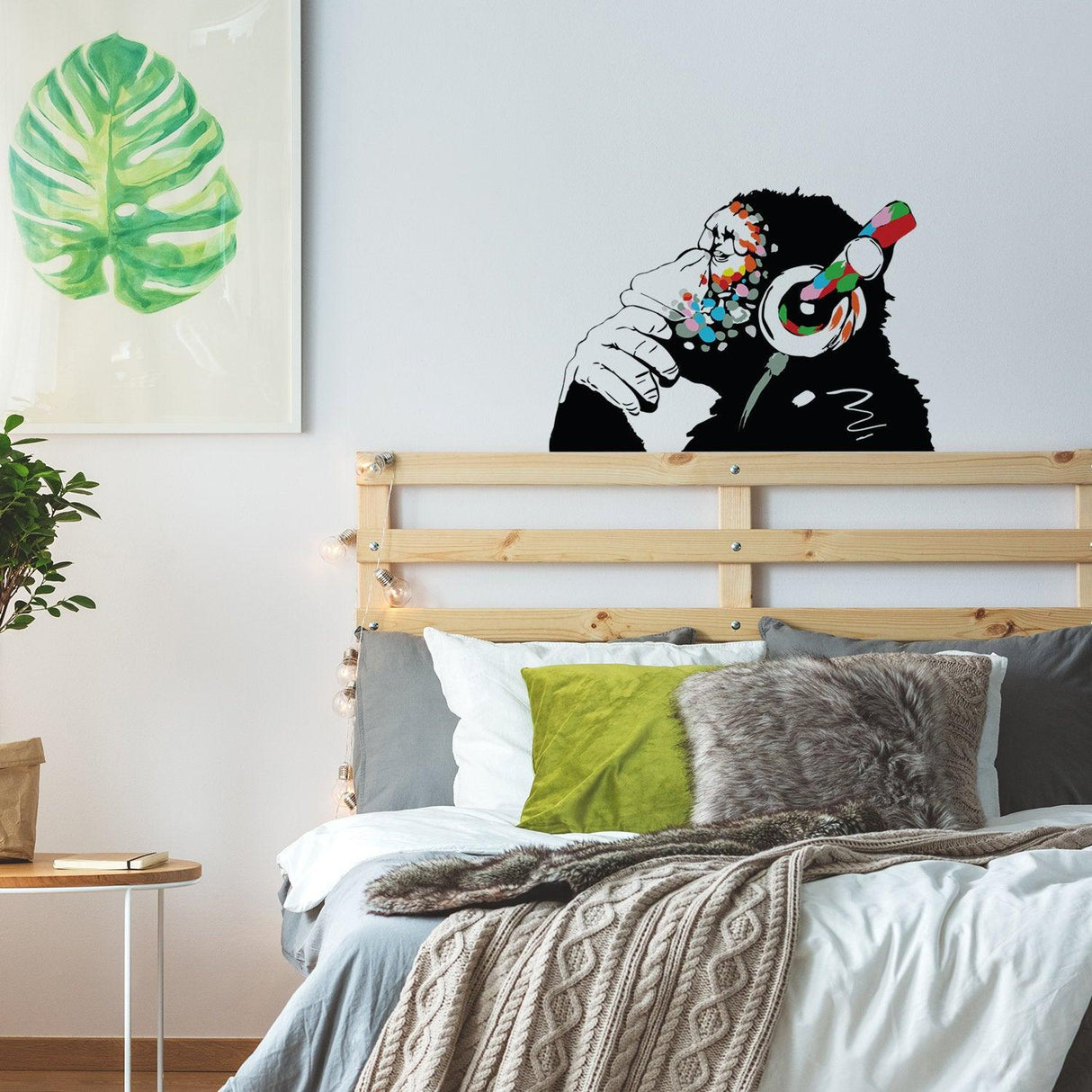 Banksy-inspired monkey sticker decal adding urban style above a modern bed with green accents.