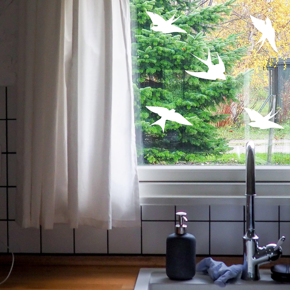 Bird strike prevention decals on a window, enhancing safety and decor in a kitchen setting.