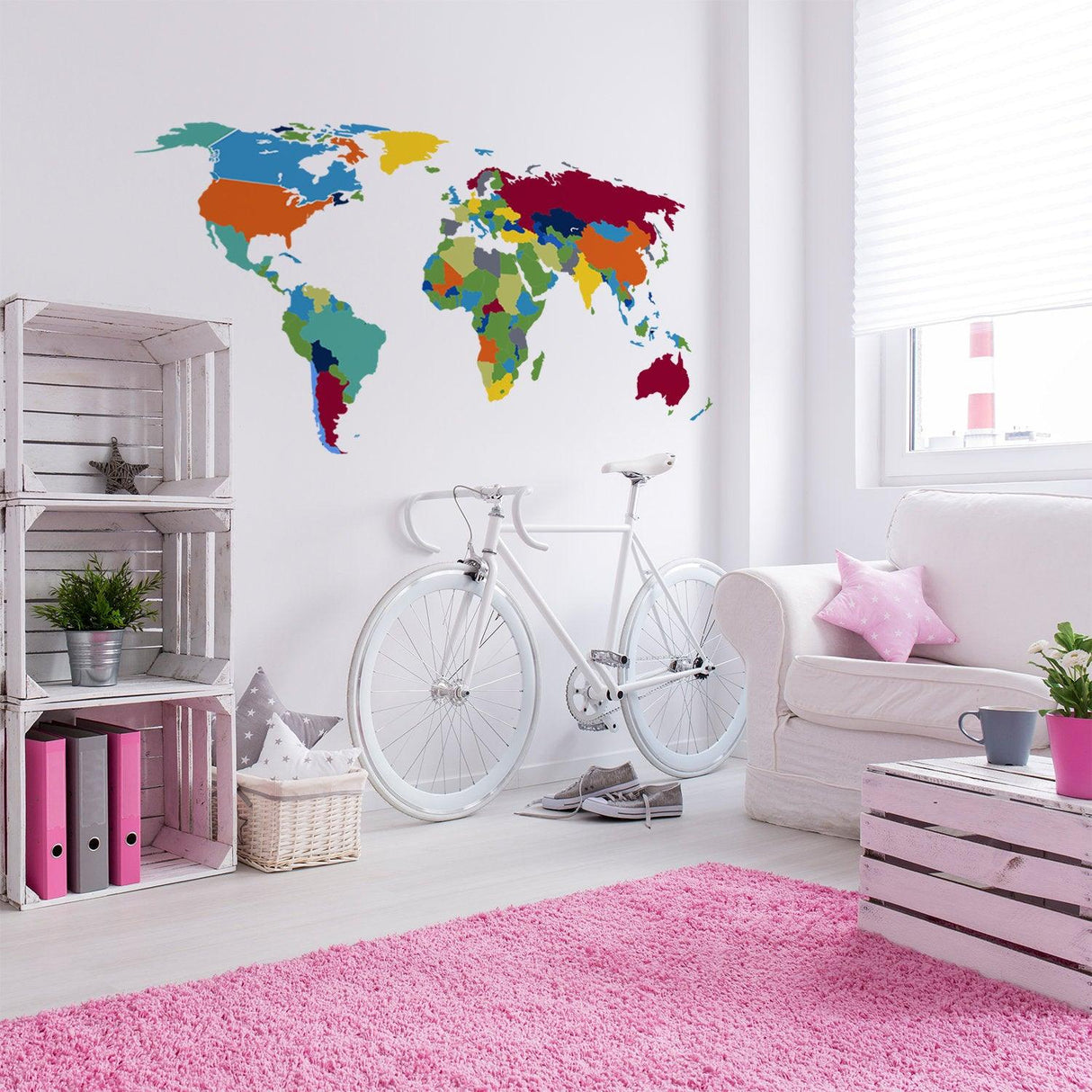 Colorful world map wall decal in a stylish living room with white bike and pink rug.