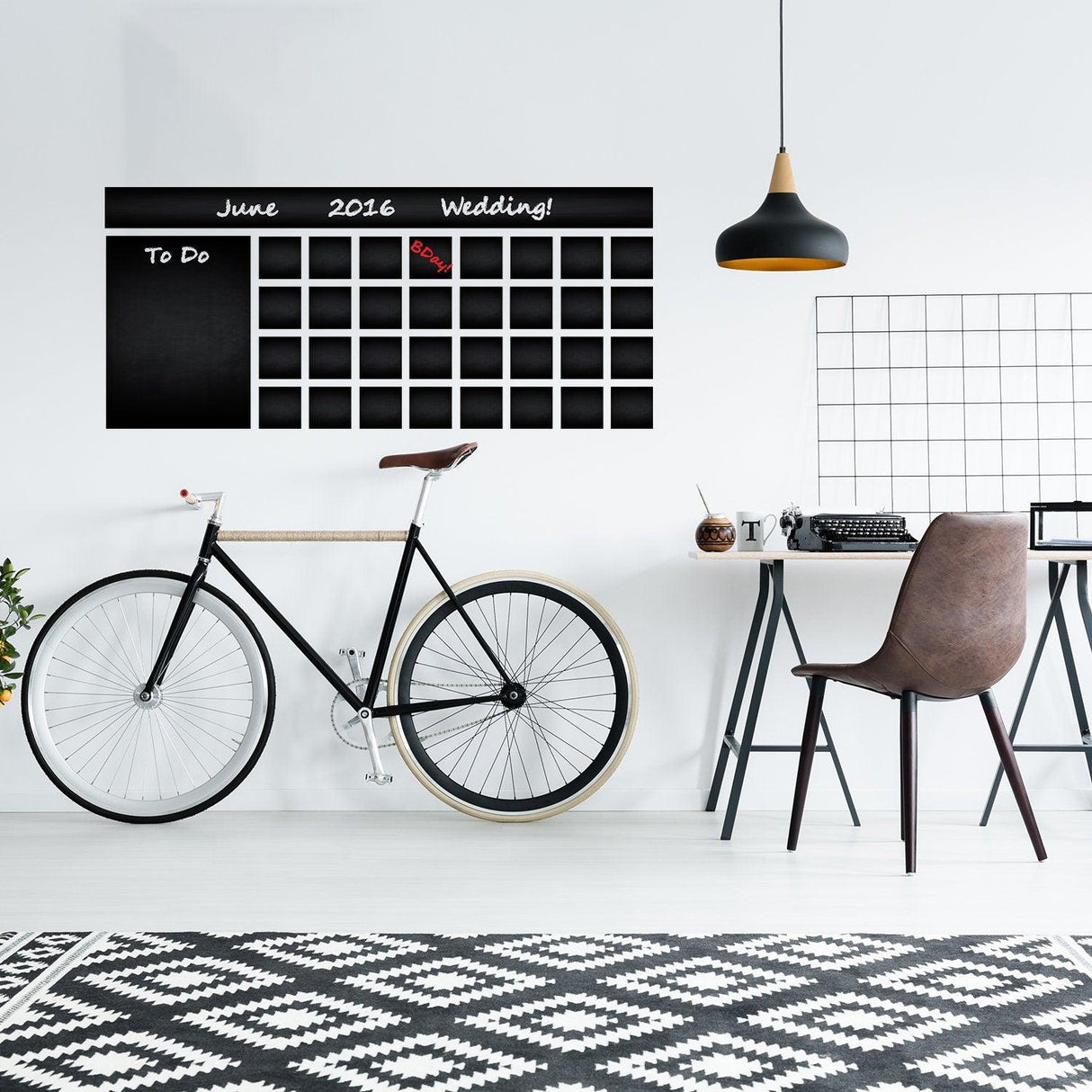 Chalkboard wall planner with calendar design in modern office setting, featuring bike and stylish decor.