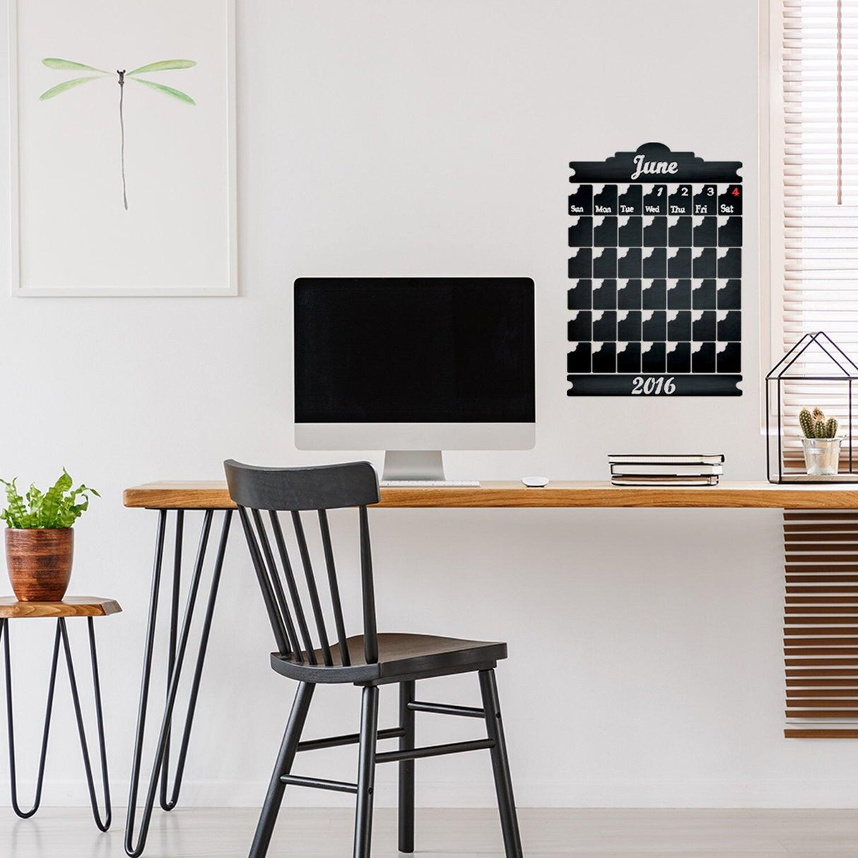 Chalkboard wall planner in modern office setup, featuring monthly calendar and workspace decorations.