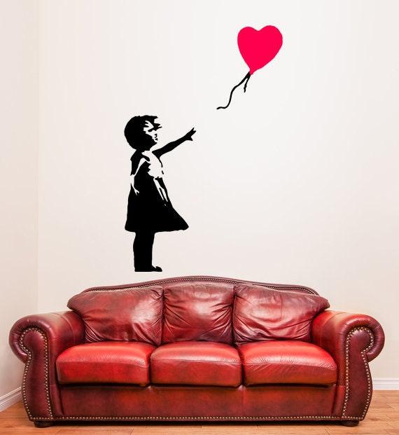 Banksy Girl With Red Balloon wall decal above a red leather couch, showcasing street art elegance.
