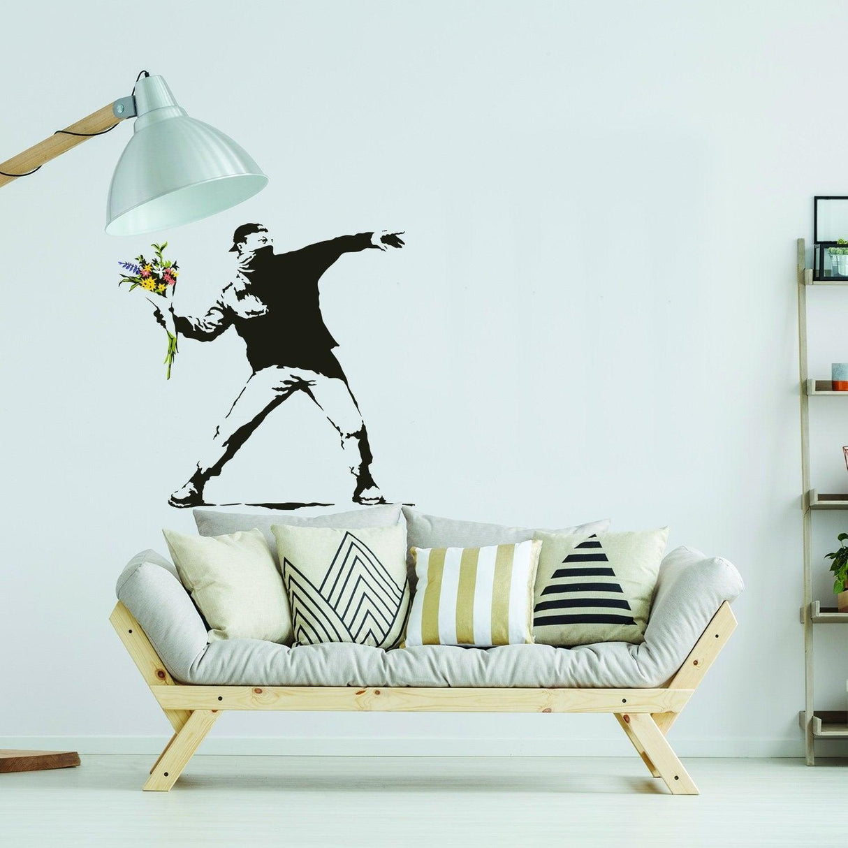 Banksy Flower Thrower wall decal in living room above a modern couch with decorative pillows.