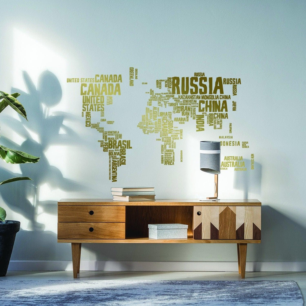 World map wall decal made of words on a living room wall above a wooden cabinet.