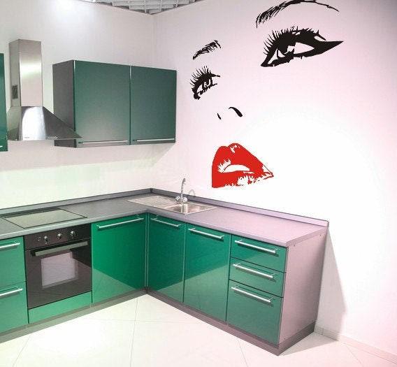 Woman eyes wall decal above green kitchen cabinets, adding elegance to modern home decor.
