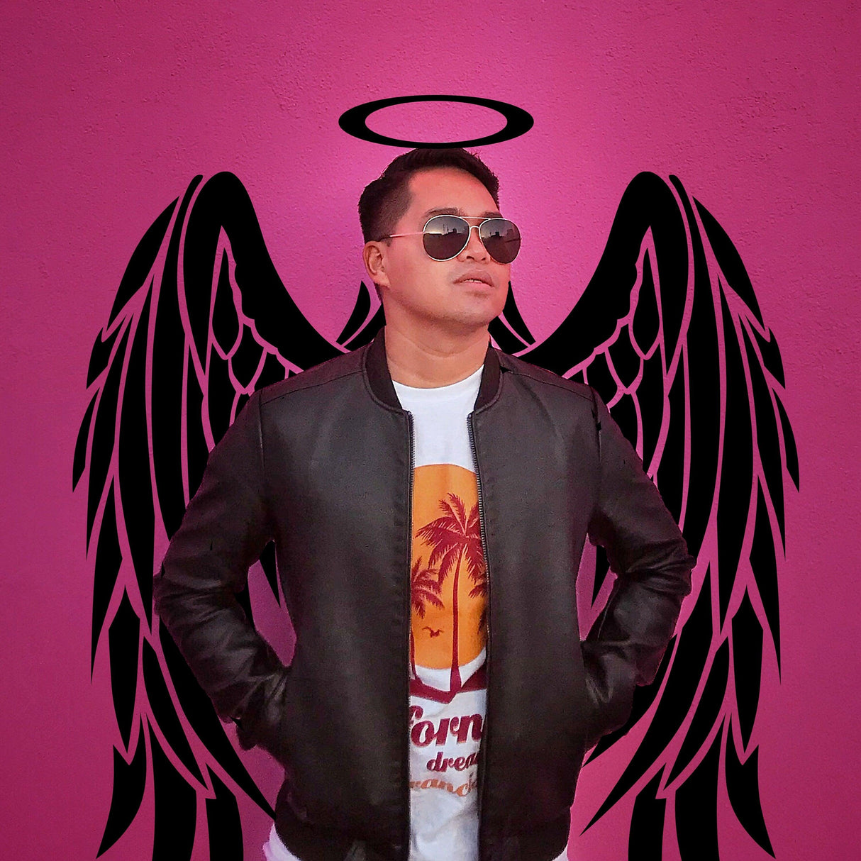 Person wearing sunglasses in front of pink angel wings mural with halo, styled against a vibrant background.