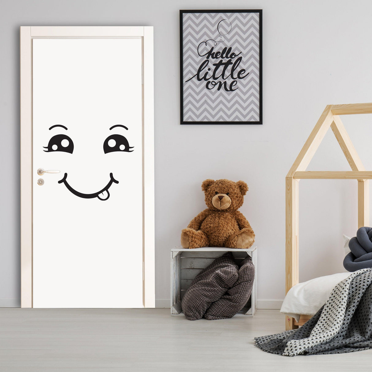 Smiling face decal on a white door in a child's room with a teddy bear and decorative elements.