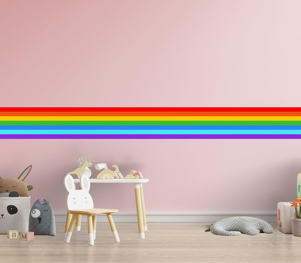 Rainbow border sticker on pink wall, adding colorful decor to a playful child's room with toys and furniture.