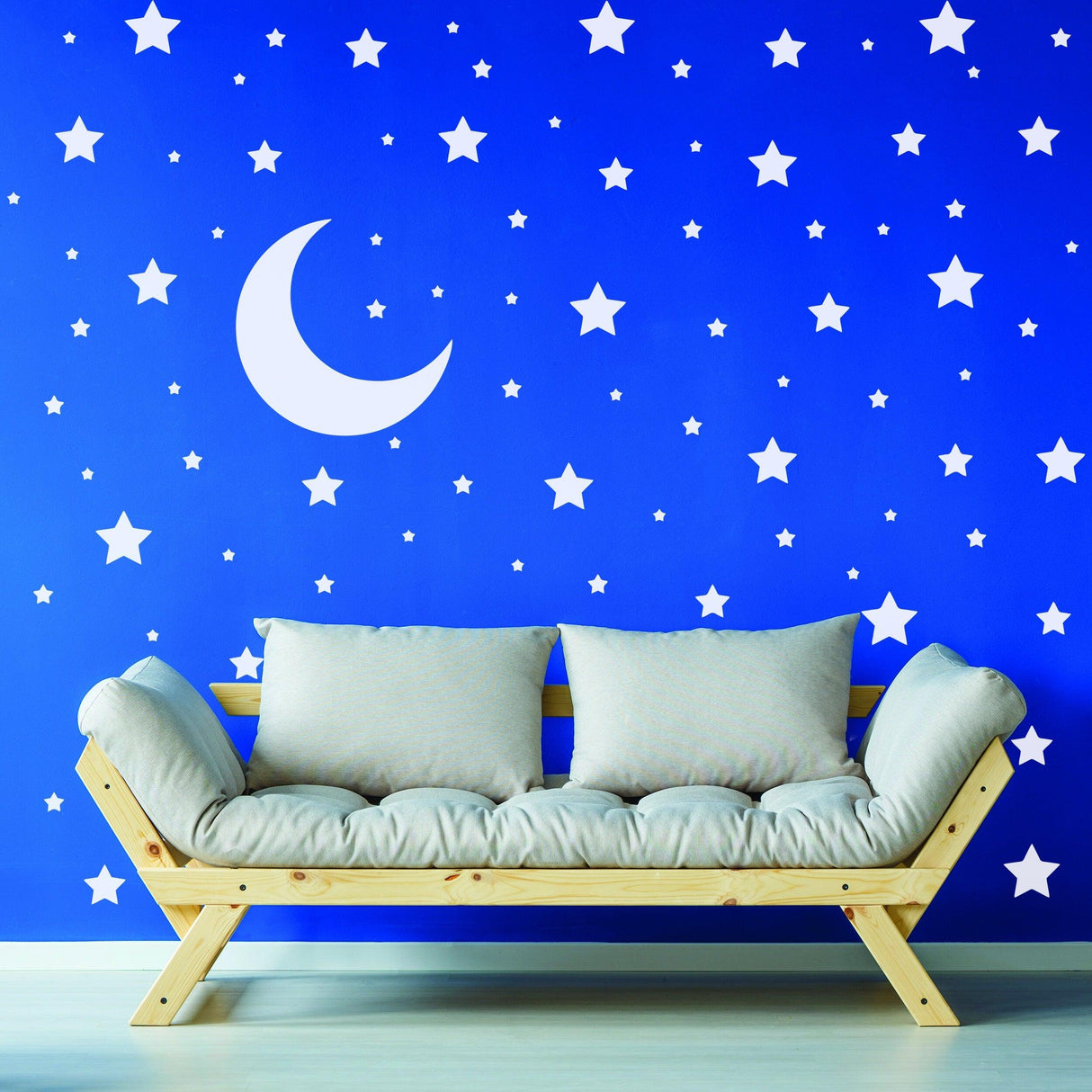 Stars and moon wall decals on blue nursery wall with a cozy wooden sofa.