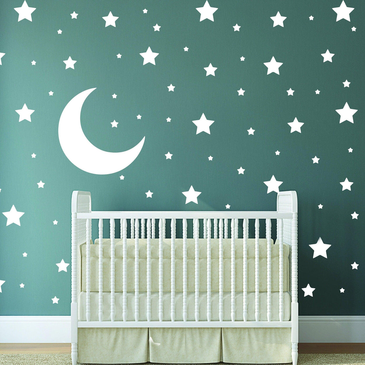Nursery with white star and moon wall decals on a green background, featuring a white crib.