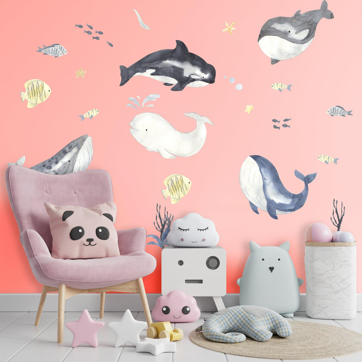 Ocean whales wall sticker in a colorful kids room with pink walls, playful decor, and soft toys for a nursery.
