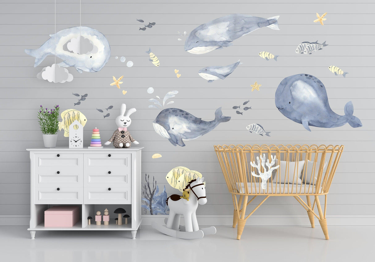 Whimsical sea whales wall sticker in a baby boy nursery with colorful fish and playful decor elements.