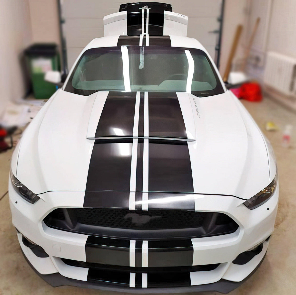 Front view of a white car with bold black racing stripes, showcasing vinyl decals for a sporty look.