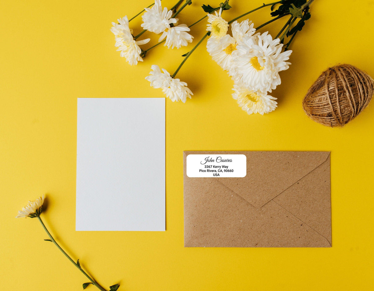 Custom clear address label on a brown envelope with a blank card and flowers on a yellow background.