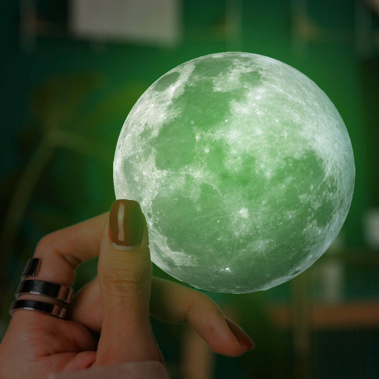 Hand holding a glowing full moon vinyl decal, showcasing its enchanting green light effect.