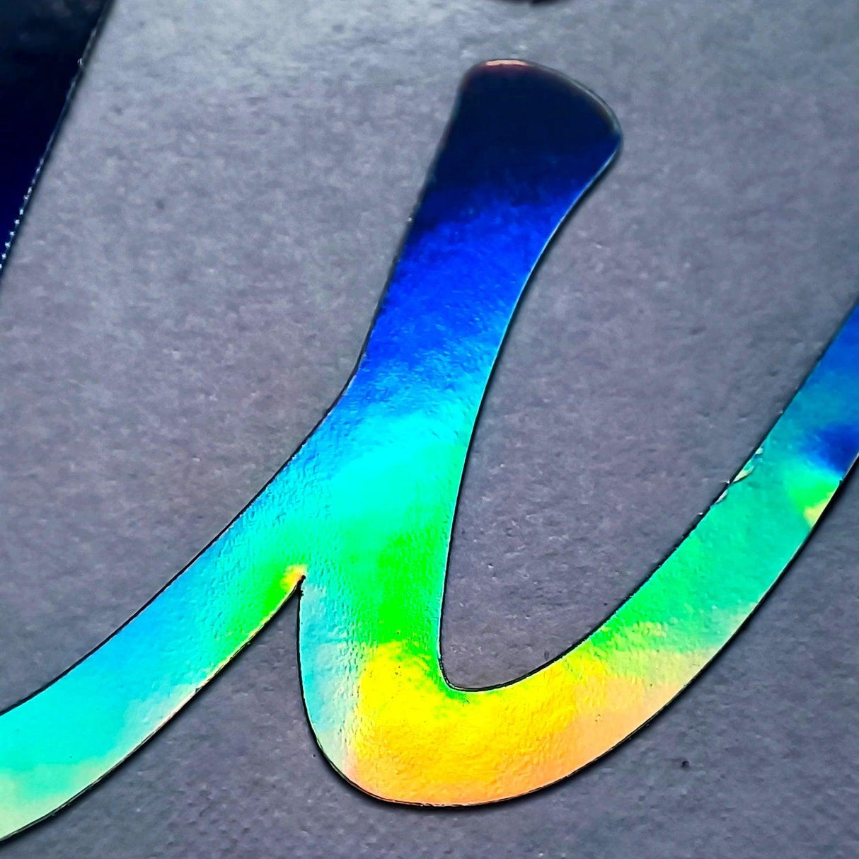 Close-up of a personalized vinyl name decal with a rainbow holographic finish, showcasing vibrant colors.