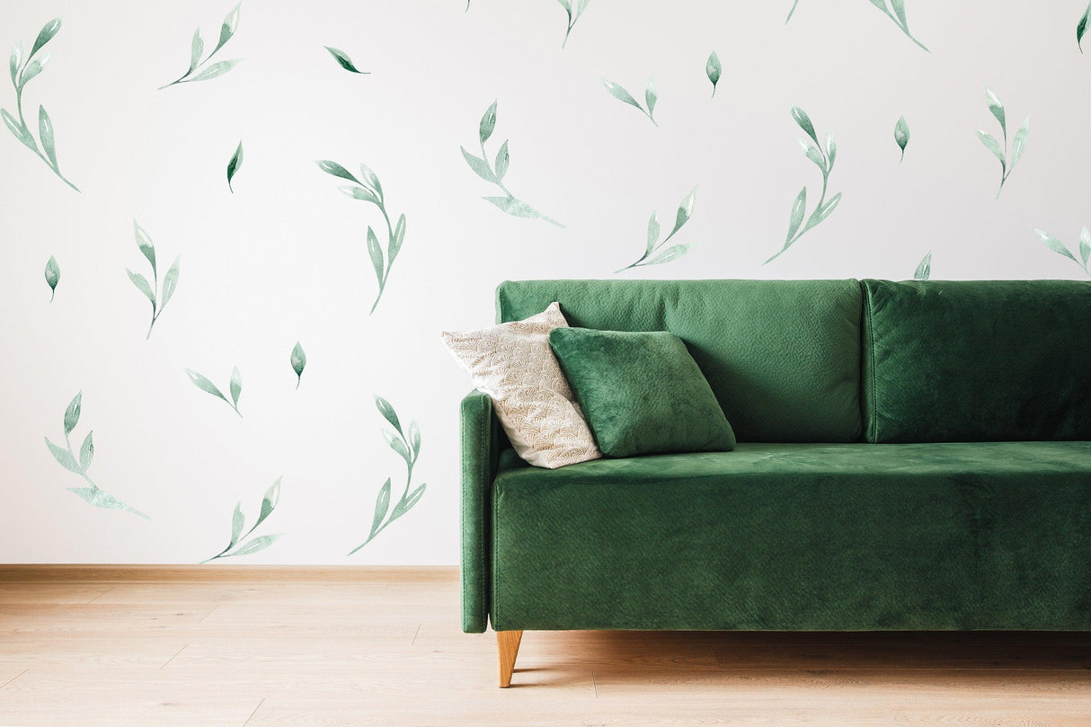 Olive botanical vinyl wall stickers on white wall above a green sofa, creating a fresh and vibrant decor.